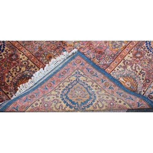 581 - A large Persian pattern wool rug, in blue, pink and yellow colourways, the central field applied wit... 