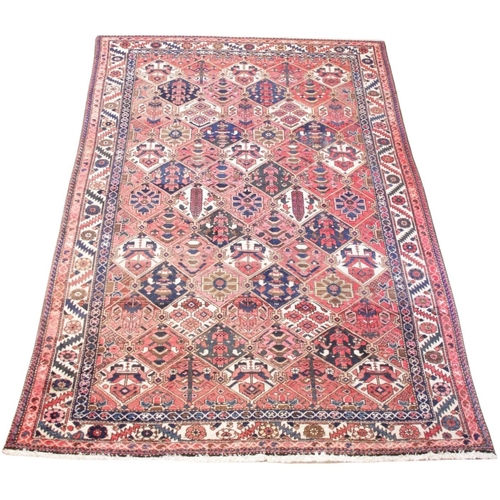 584 - A Caucasian wool rug, in red, blue and ivory colourways, the central field with seven by five rows o... 