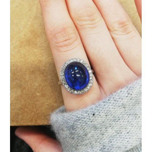 192 - An early 20th century sapphire and diamond cluster ring, the central oval sapphire cabochon measurin... 