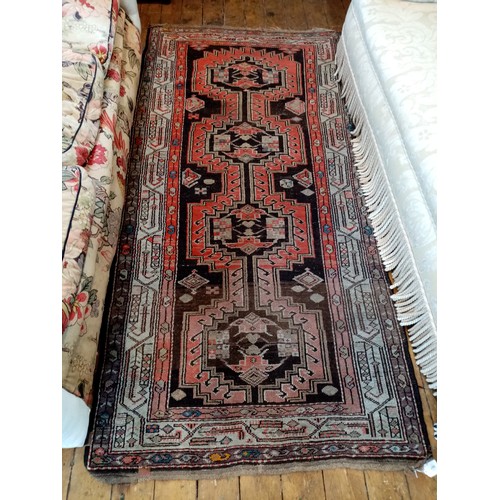 587 - A Caucasian wool rug, in red and black colourways, the central field with four linked geometric meda... 