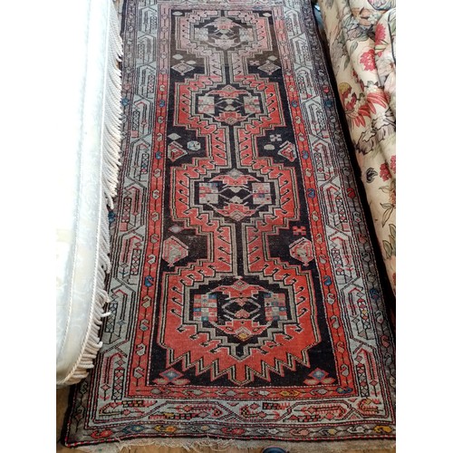 587 - A Caucasian wool rug, in red and black colourways, the central field with four linked geometric meda... 