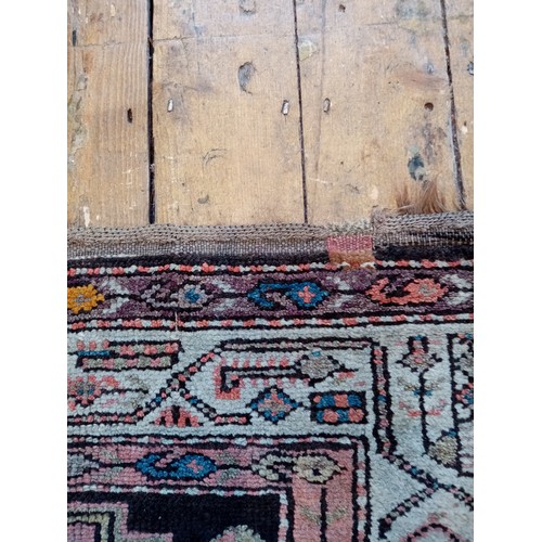 587 - A Caucasian wool rug, in red and black colourways, the central field with four linked geometric meda... 