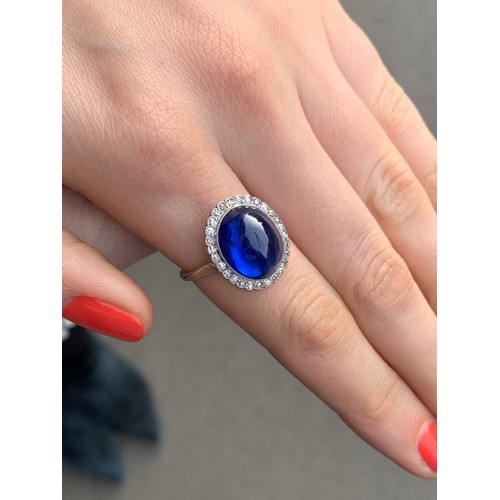 192 - An early 20th century sapphire and diamond cluster ring, the central oval sapphire cabochon measurin... 