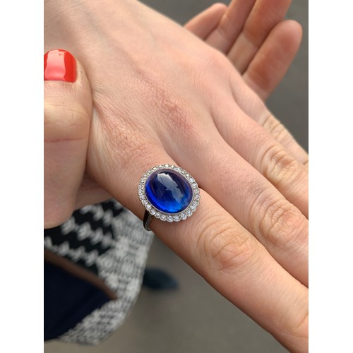 192 - An early 20th century sapphire and diamond cluster ring, the central oval sapphire cabochon measurin... 