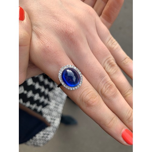 192 - An early 20th century sapphire and diamond cluster ring, the central oval sapphire cabochon measurin... 