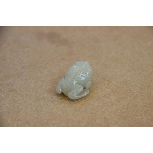 427 - A Chinese pale jade toad, 19th century, the celadon coloured carving modelled grasping a fruiting vi... 