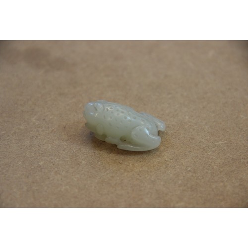 427 - A Chinese pale jade toad, 19th century, the celadon coloured carving modelled grasping a fruiting vi... 