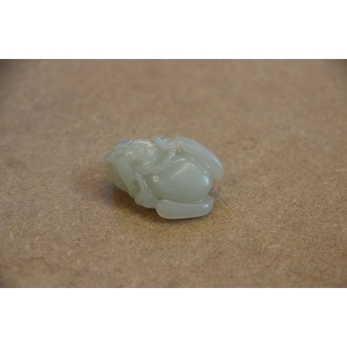 427 - A Chinese pale jade toad, 19th century, the celadon coloured carving modelled grasping a fruiting vi... 