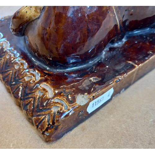 477 - An English treacle glazed earthenware tobacco box of large proportions, 19th century, the cover mode... 