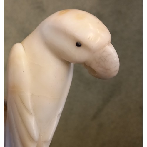 251 - An Art Deco style carved alabaster model of a parrot, circa 1930, modelled upon a perch, 22.5cm high