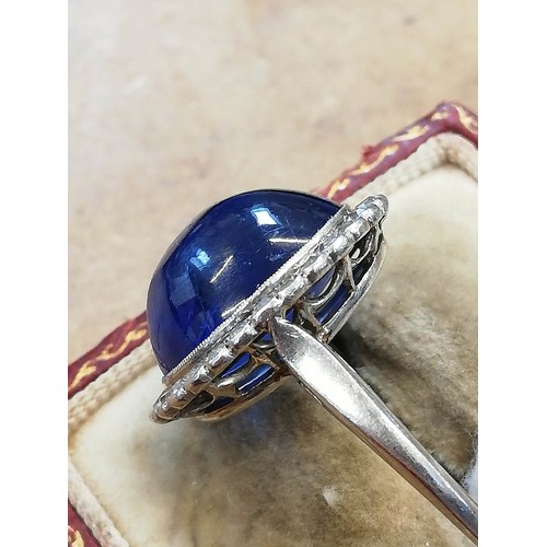 192 - An early 20th century sapphire and diamond cluster ring, the central oval sapphire cabochon measurin... 