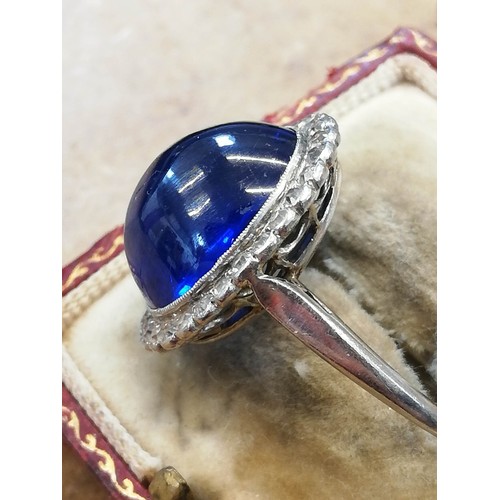 192 - An early 20th century sapphire and diamond cluster ring, the central oval sapphire cabochon measurin... 