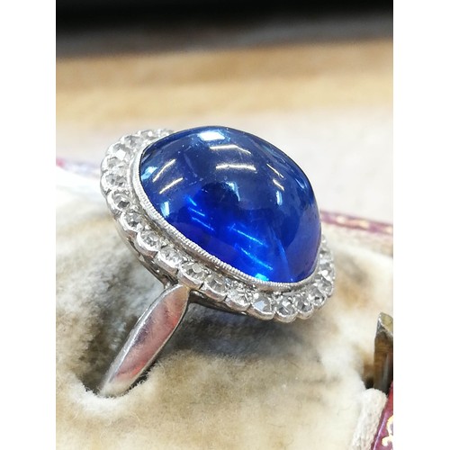 192 - An early 20th century sapphire and diamond cluster ring, the central oval sapphire cabochon measurin... 