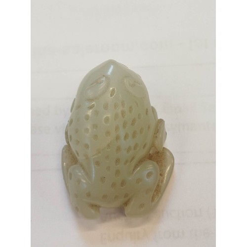 427 - A Chinese pale jade toad, 19th century, the celadon coloured carving modelled grasping a fruiting vi... 