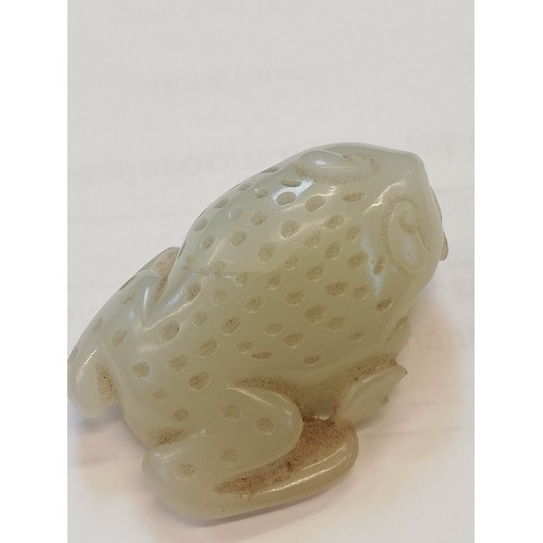 427 - A Chinese pale jade toad, 19th century, the celadon coloured carving modelled grasping a fruiting vi... 