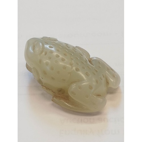 427 - A Chinese pale jade toad, 19th century, the celadon coloured carving modelled grasping a fruiting vi... 