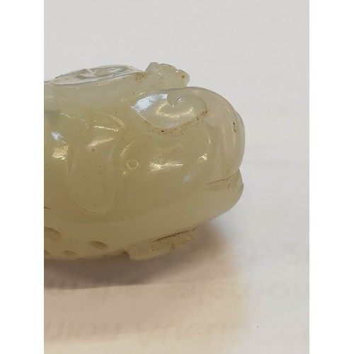 427 - A Chinese pale jade toad, 19th century, the celadon coloured carving modelled grasping a fruiting vi... 