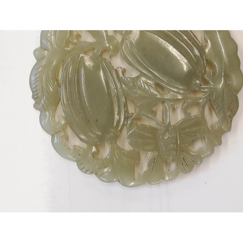 413 - A Chinese jade roundel, of reticulate circular form, carved with vines and two fruiting gourds with ... 