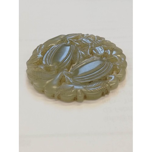 413 - A Chinese jade roundel, of reticulate circular form, carved with vines and two fruiting gourds with ... 