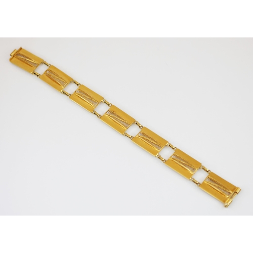 219 - A yellow metal panel bracelet, designed as a row of seven rectangular panels, each with pierced scro... 