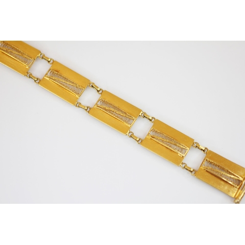 219 - A yellow metal panel bracelet, designed as a row of seven rectangular panels, each with pierced scro... 