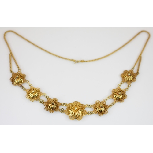 222 - A yellow metal floral filigree necklace, the front section designed as seven graduated gold coloured... 