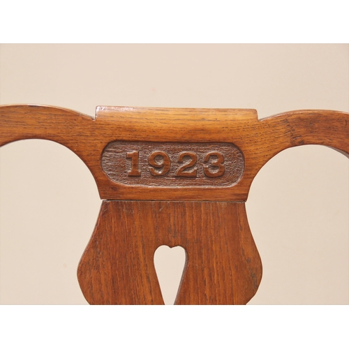 854 - A 1923 oak Eisteddfod chair, the top rail carved with the year above a pierced splat and board seat,... 