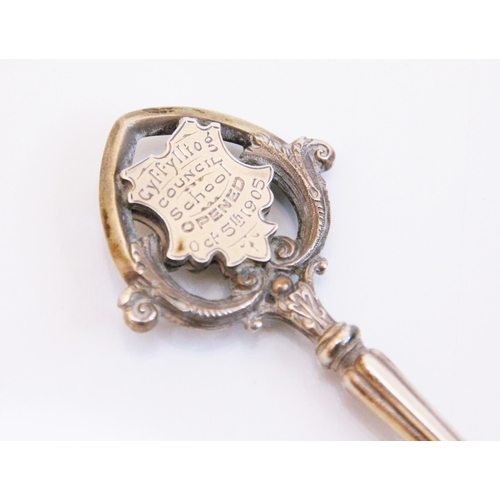 93 - A silver coloured presentation key, the key with two cartouches within an openwork scroll border,  e... 