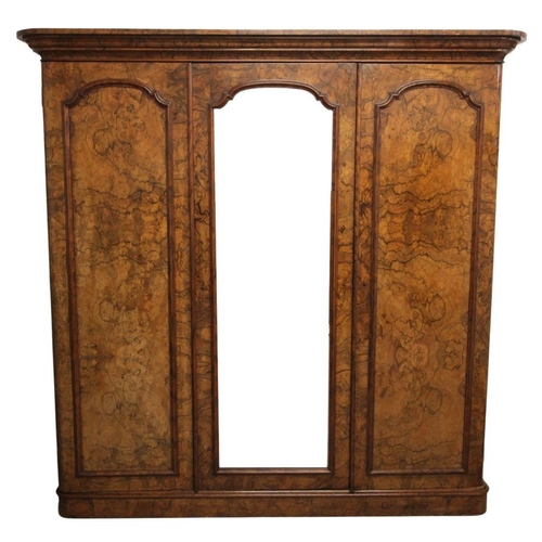 819 - A Victorian figured walnut triple wardrobe, the moulded ogee cornice over a central mirrored door an... 