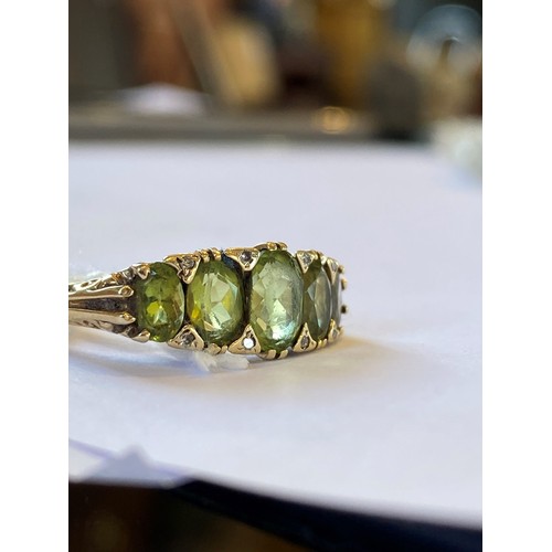 228 - A 9ct gold peridot five stone ring, the ring with central oval mixed cut peridot measuring 6.48 x 4.... 