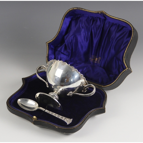 62 - A George V silver cased two handled bowl and spoon, Finnigans Ltd, Dublin 1912, the bowl with cast s... 