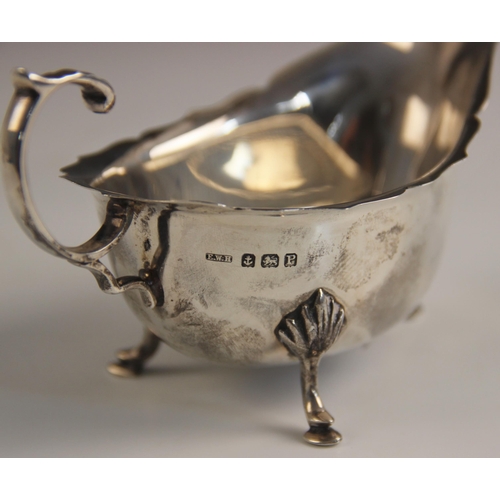 70 - A George V silver sauce boat, Adie Brothers Ltd, Birmingham 1925, with scroll handle upon three shel... 