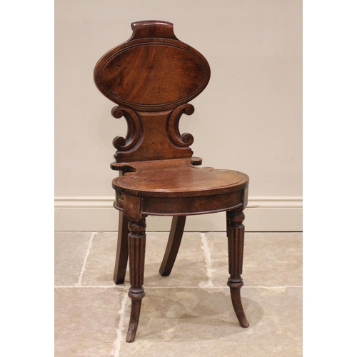 762 - A Regency mahogany hall chair, the oval panel back with moulded 'C' scroll detail over the conformin... 