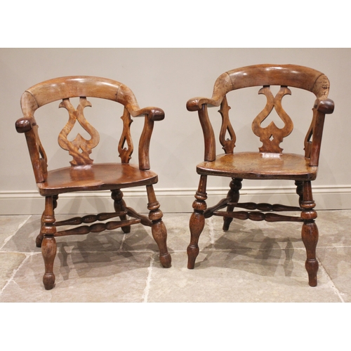 800 - A near pair of Victorian elm and beech smokers bow elbow chairs, each with a down swept arm rest and... 