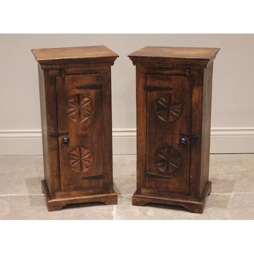 841 - A pair of hardwood bedside cabinets, the single doors carved with a pair of flowerhead roundels, mou... 