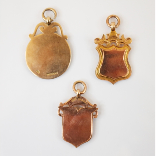 174 - A selection of three 9ct gold fobs, to include a circular example with plain polished central shield... 