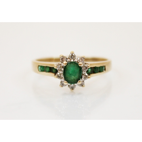 208 - An emerald and diamond yellow metal ring, the central oval cut emerald in a surround of round cut di... 