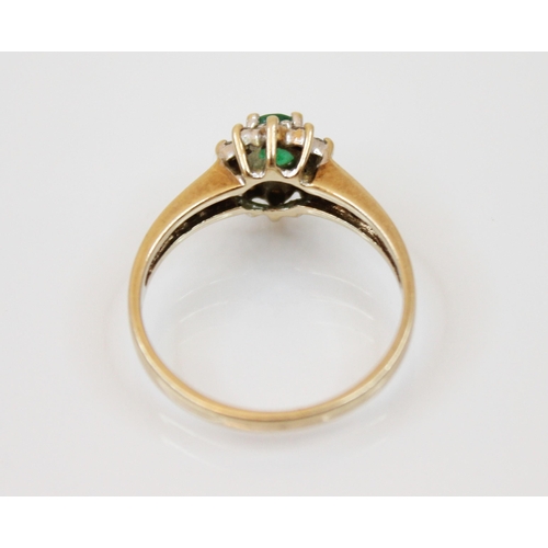 208 - An emerald and diamond yellow metal ring, the central oval cut emerald in a surround of round cut di... 