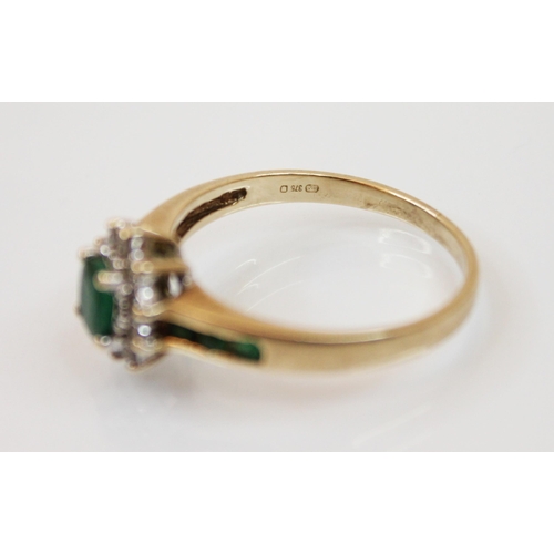 208 - An emerald and diamond yellow metal ring, the central oval cut emerald in a surround of round cut di... 