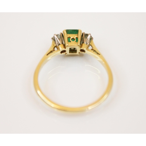 235 - A diamond and emerald 18ct gold three stone ring, the central rectangular cut emerald with round cut... 