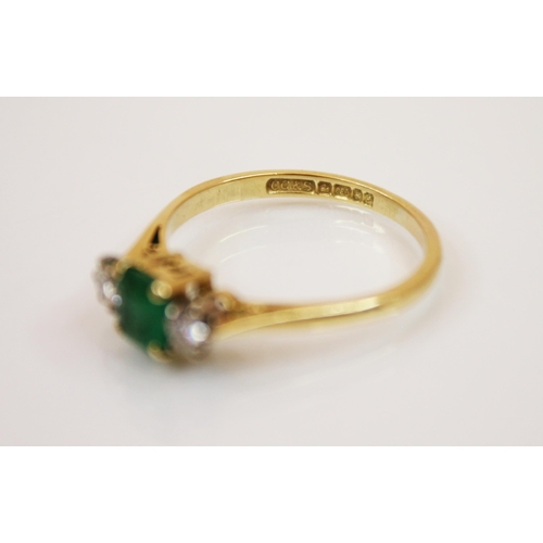 235 - A diamond and emerald 18ct gold three stone ring, the central rectangular cut emerald with round cut... 