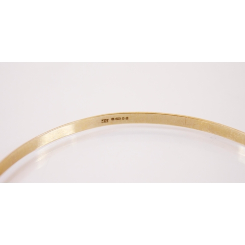 178 - A 9ct gold bangle, the bangle with a continuous cross decoration, marked for ‘JC London’ with a whit... 