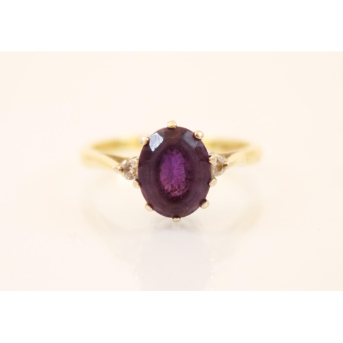 179 - An amethyst and diamond three stone ring, the central oval cut amethyst (estimated 2 carats) with tw... 