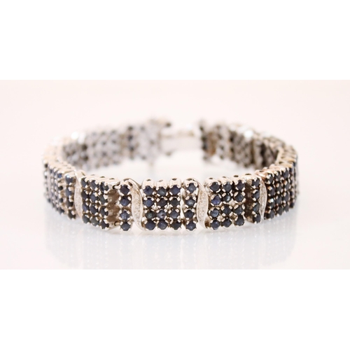 214 - A diamond and sapphire panel bracelet, designed as a continuation of four rows of round cut sapphire... 