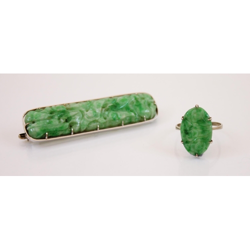 223 - An Art Deco style jade ring, the claw set carved oval panel ring decorated as flowers, 2cm long, mou... 