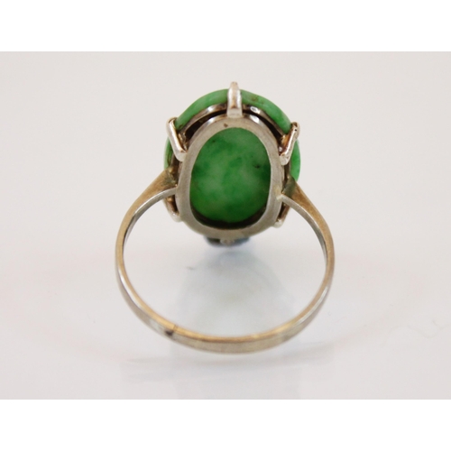 223 - An Art Deco style jade ring, the claw set carved oval panel ring decorated as flowers, 2cm long, mou... 