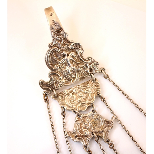 34 - A silver coloured Victorian chatelaine, the clip  depicting a seated lady and scrolling decoration, ... 