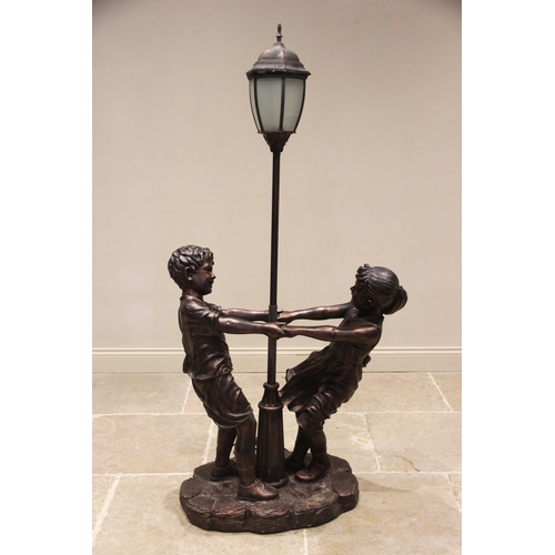 541 - A composite bronze patina figural standard lamp, late 20th century, the lamp modelled as a street la... 