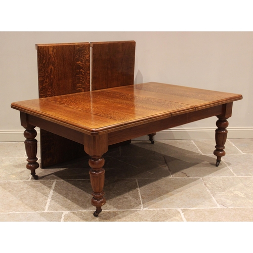 780 - A Victorian oak extending dining table, the rectangular moulded top upon fluted vase shaped legs cul... 