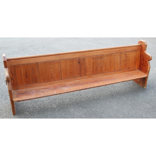 581 - A Victorian pitch pine pew, the shaped end supports united by a panelled back, board seat and rear b... 